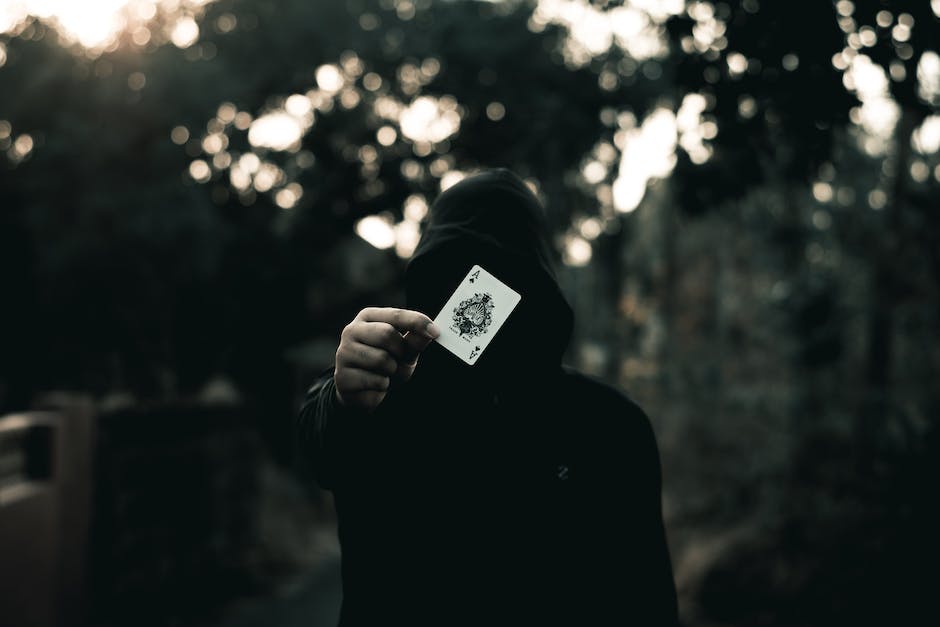 Description: The Joker holding a playing card with his twisted smile, representing the dangerous magnetism that disorients and attracts.
