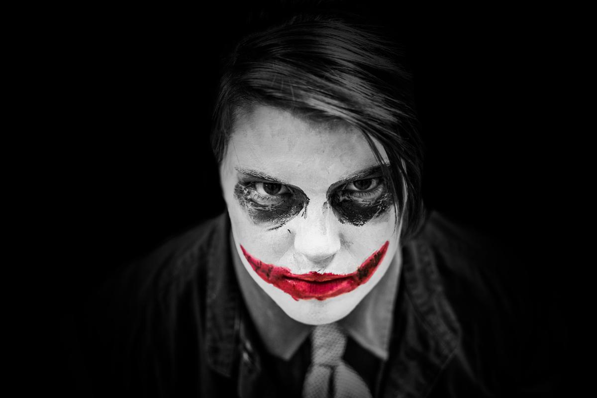 Icona del Joker con pelle bianca, capelli verdi e un ghigno inquietante sul volto, rappresentando il suo aspetto iconico e distintivo.