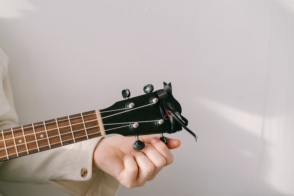 Illustration of someone tuning an ukulele with a chromatic tuner.